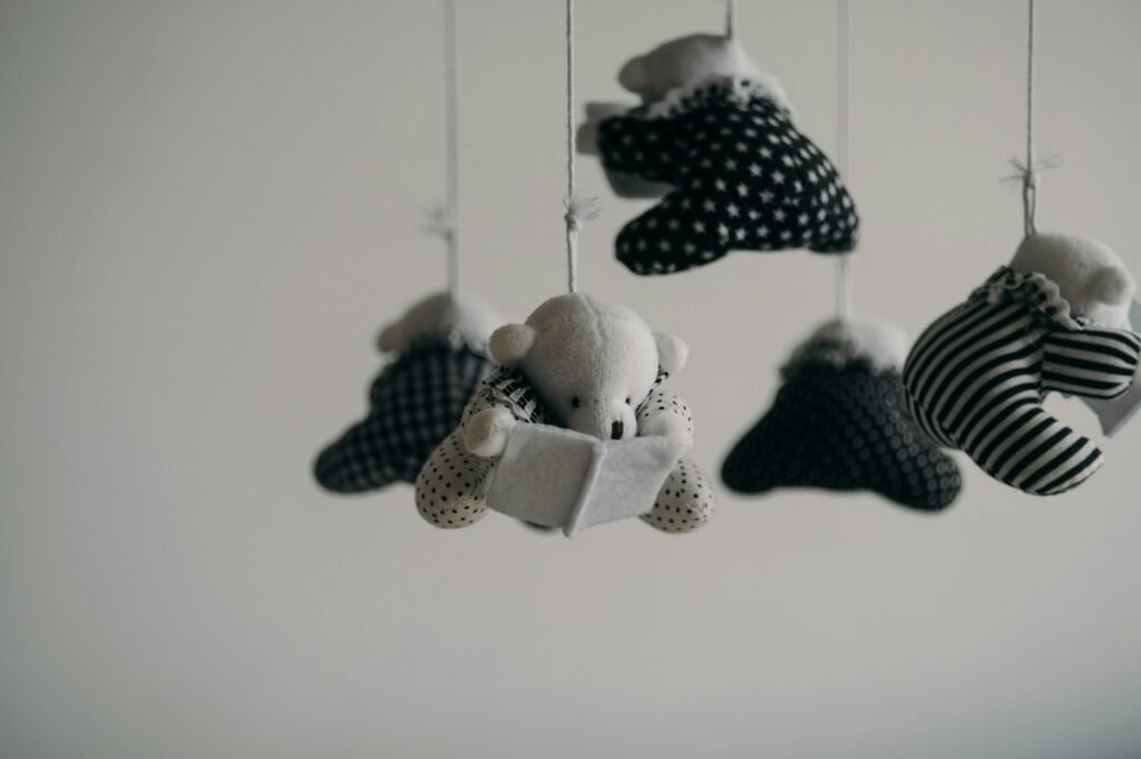 White crib with a mobile hanging above it in a plain, uncluttered nursery