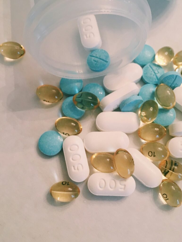 Assorted tablets and capsules scattered near an open pill organizer