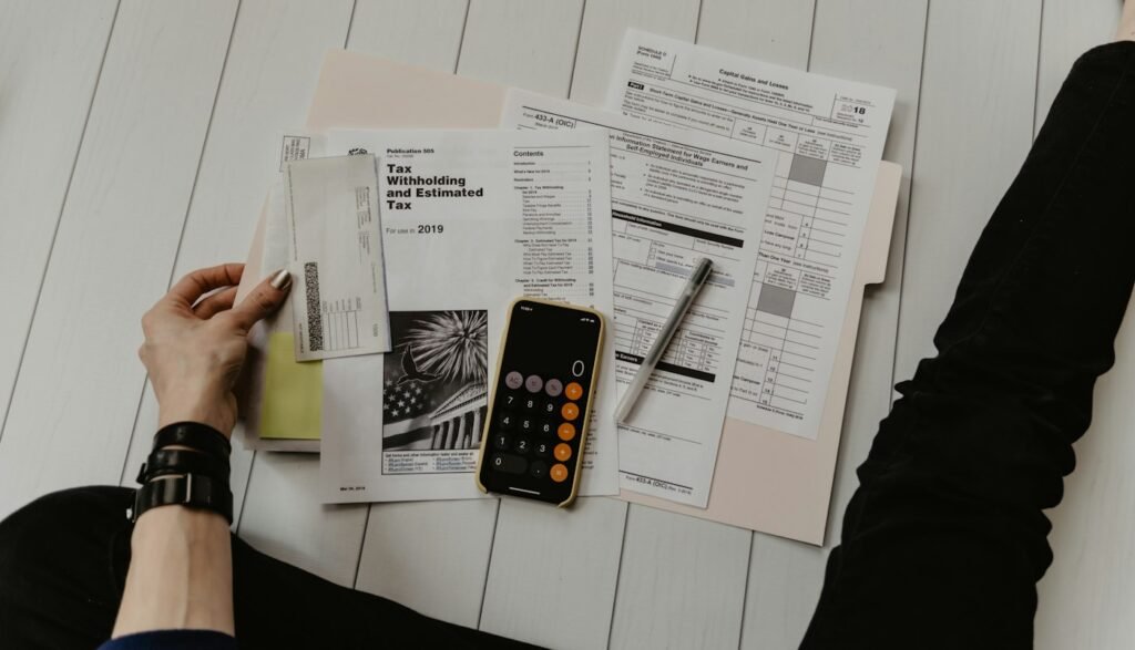 Paperwork, a calculator, and a pen spread out while someone sorts through documents