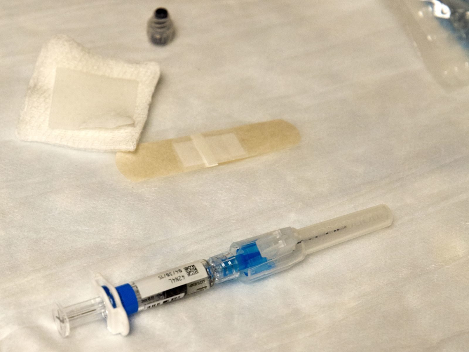 A flu vaccine syringe with an alcohol pad and bandage