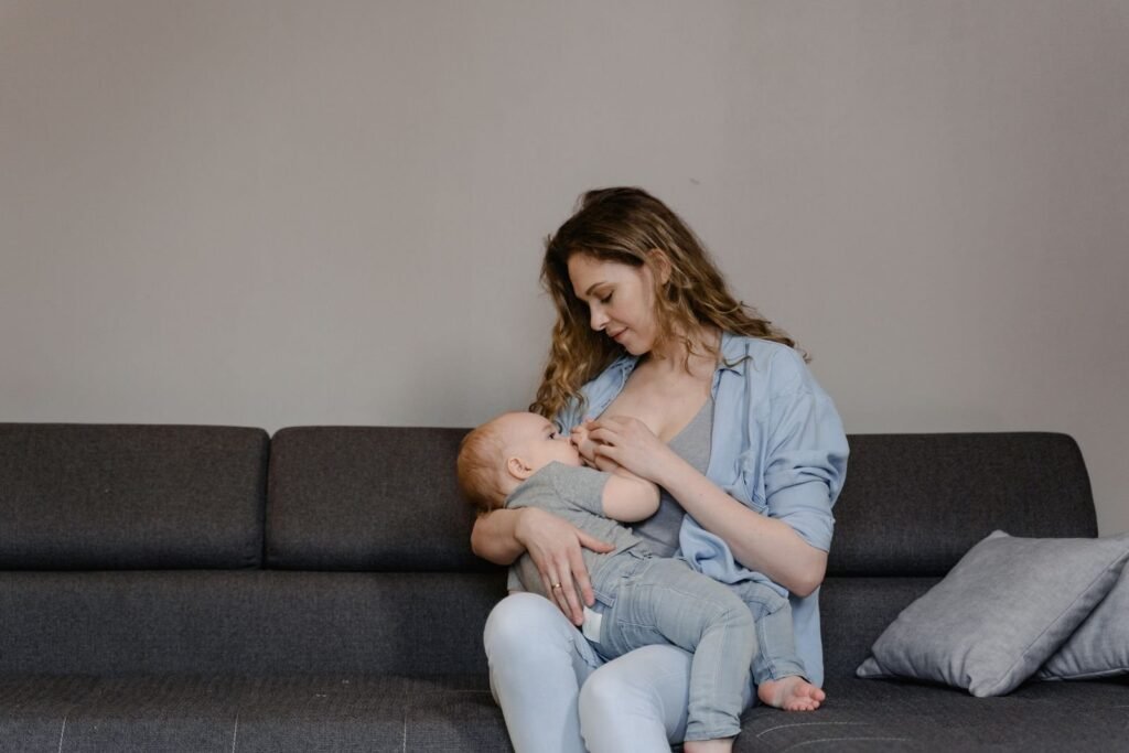 Mother breastfeeding her baby while sitting on a couch