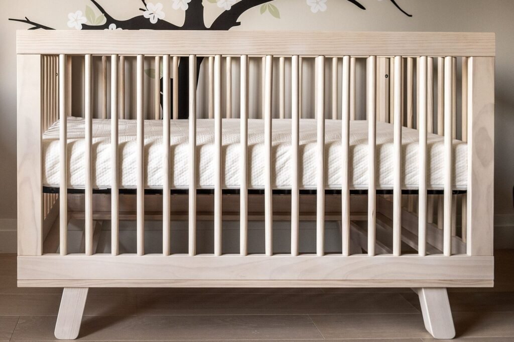 Empty wooden crib with a firm, bare mattress