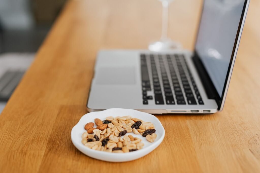 Bowl of nuts and dried fruit next to a laptop as a healthy work snack