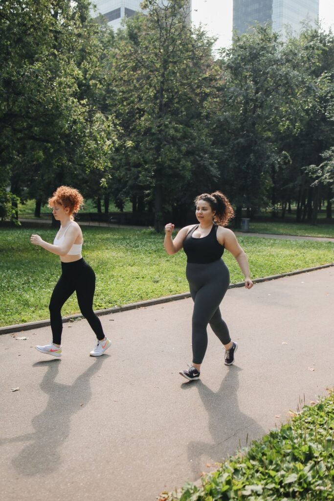 Two women brisk walking on a park path for weekly exercise