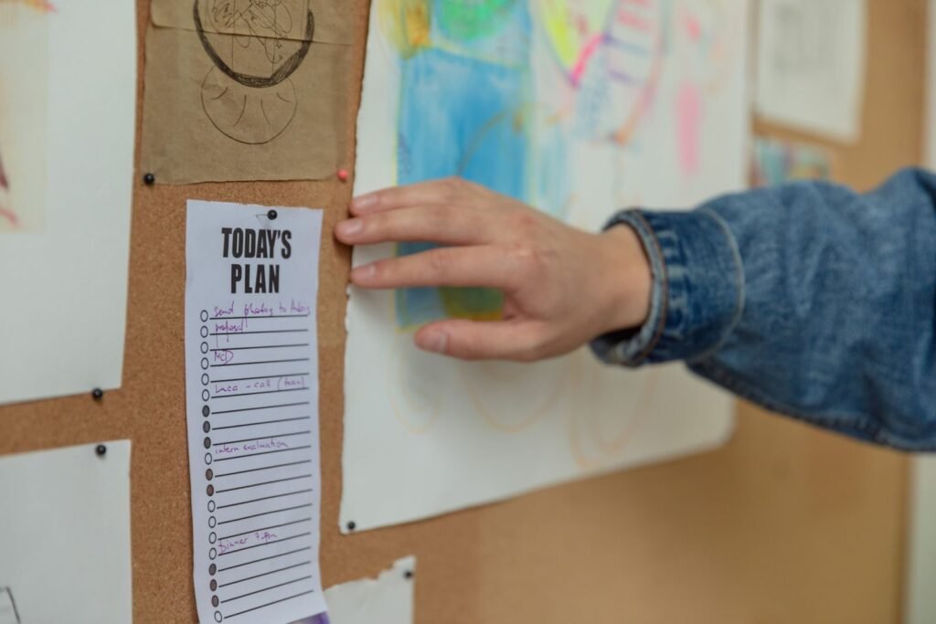 Hand pinning a daily plan to a cork board as part of a family command center