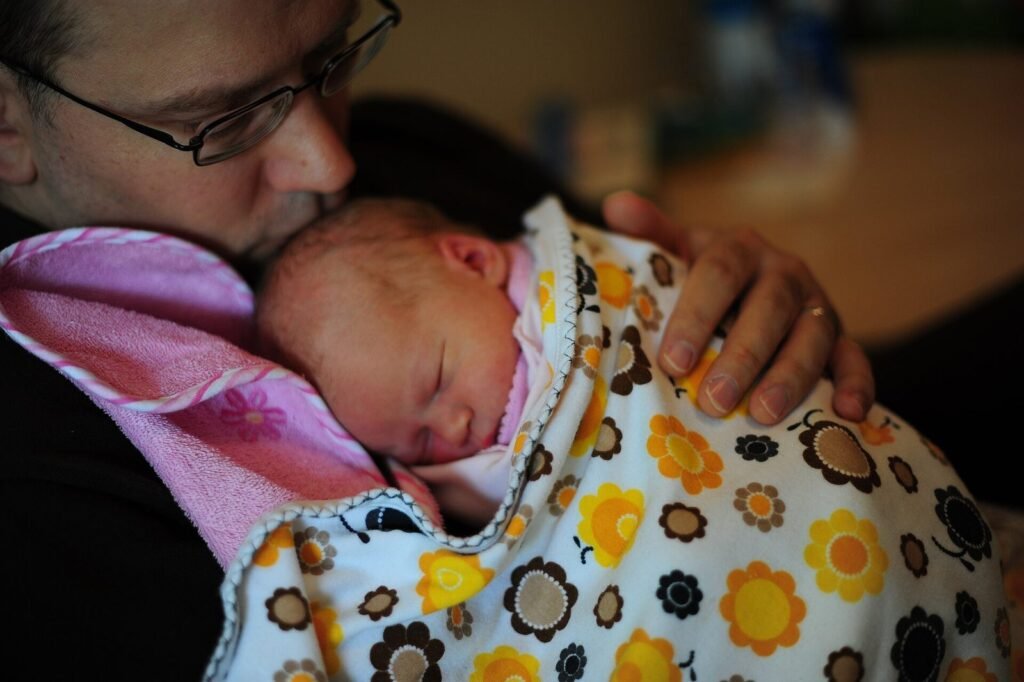 Father holding his sleeping newborn wrapped in a blanket