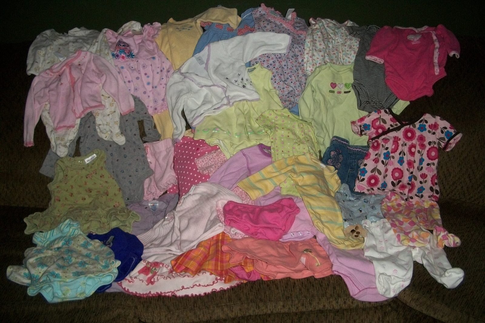Pile of secondhand baby clothes laid out for sorting